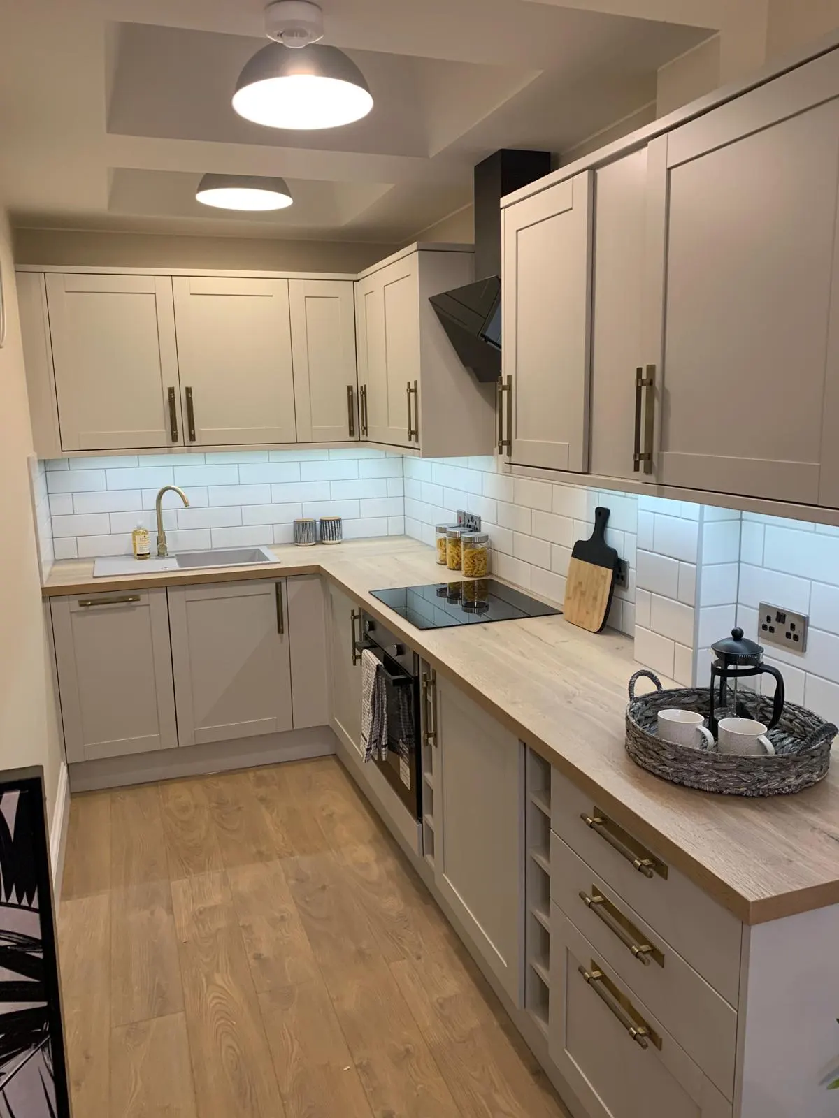 Completed kitchen with light shaker cabinets, timber-effect worktop and tiled splashback